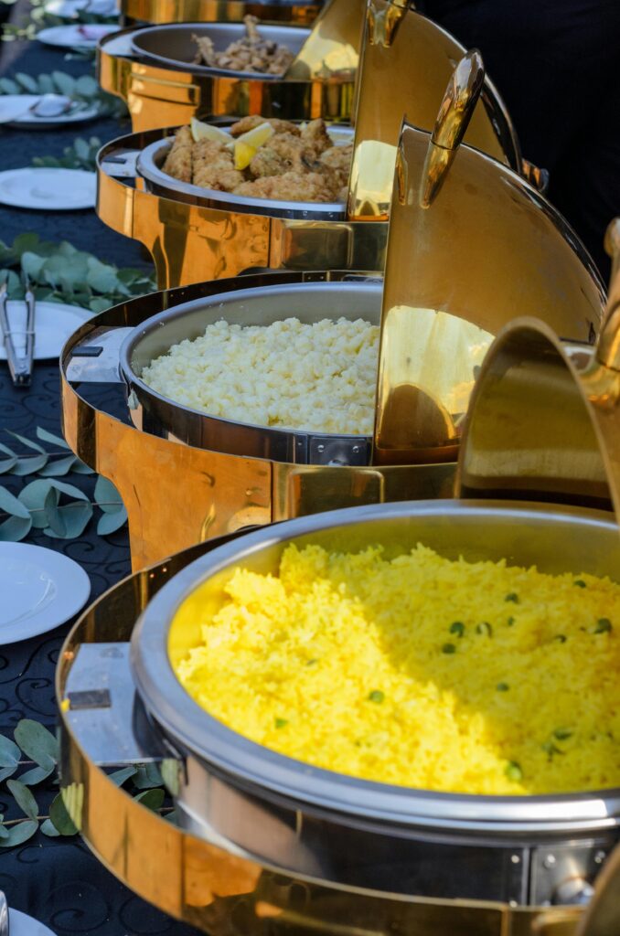 pexels photo 12253094 12253094 A vibrant buffet spread featuring yellow rice and various options in elegant chafing dishes.